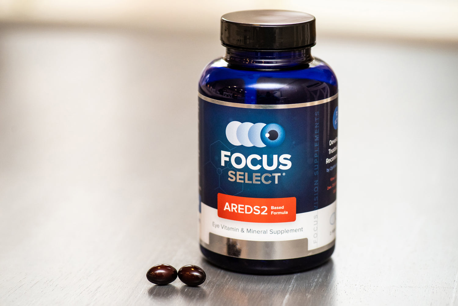 Bottle of Focus Select supplement with two capsules on a light surface
